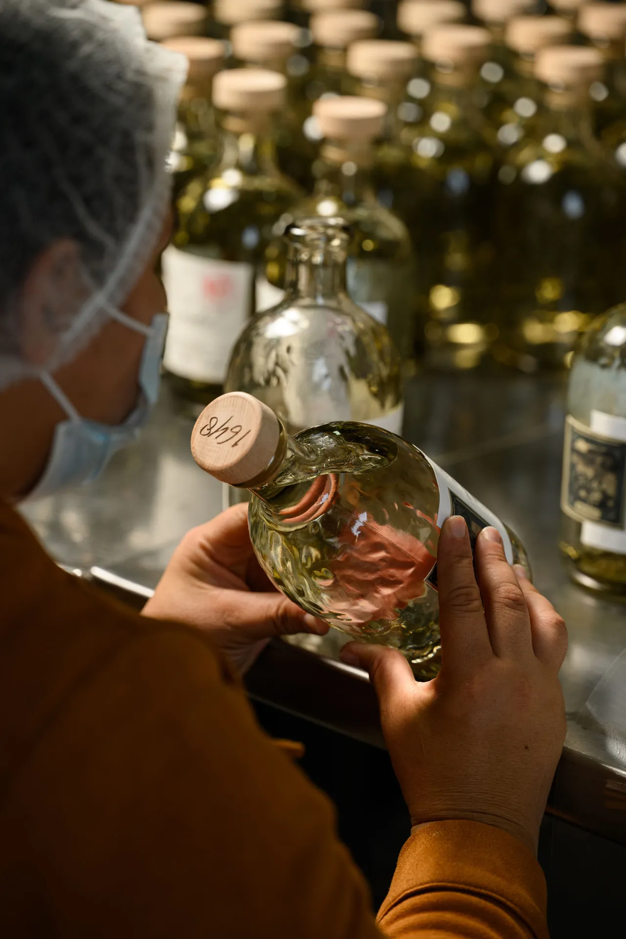 A bottling worker checks a numbered, cork-stoppered bottle by hand