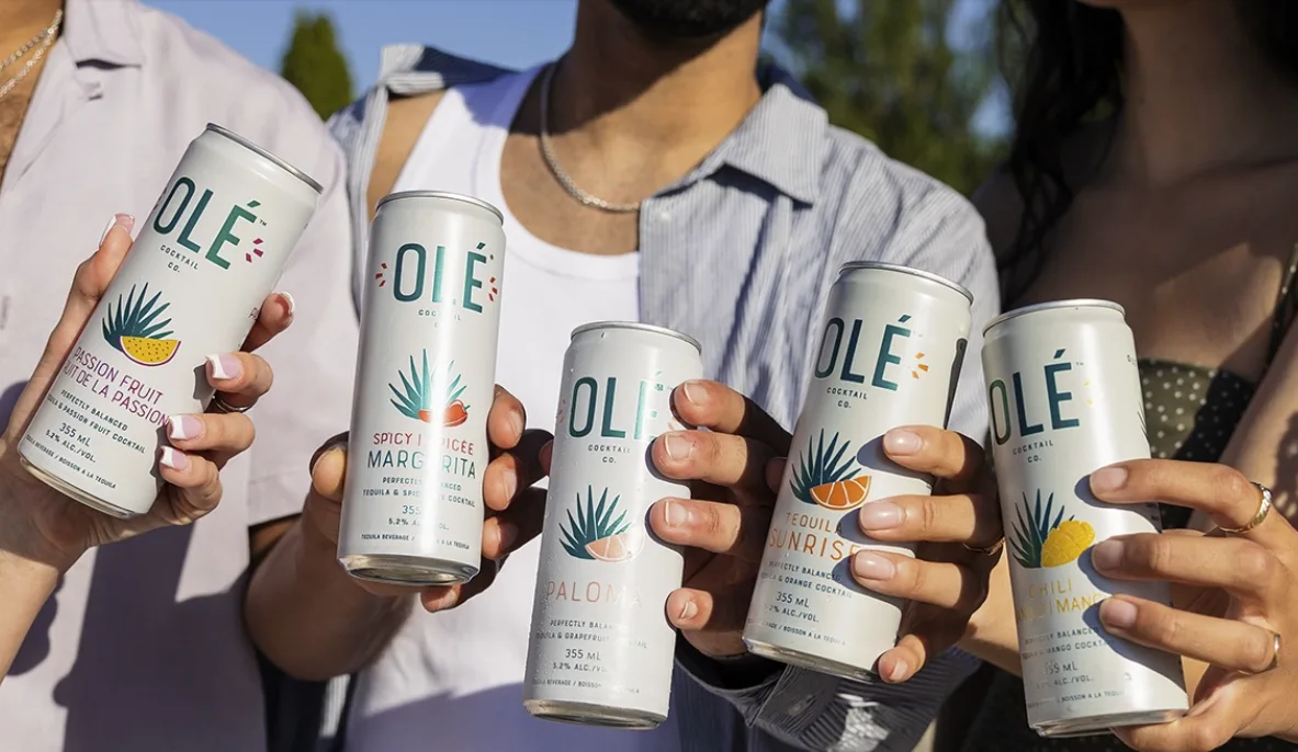 Friends raise five cans of Olé Cocktail Co — passion fruit, spicy margarita, paloma, tequila sunrise and chili mango — in the sun